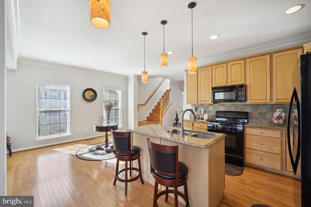 a kitchen with stainless steel appliances granite countertop a stove top oven a sink dishwasher and white cabinets with wooden floor