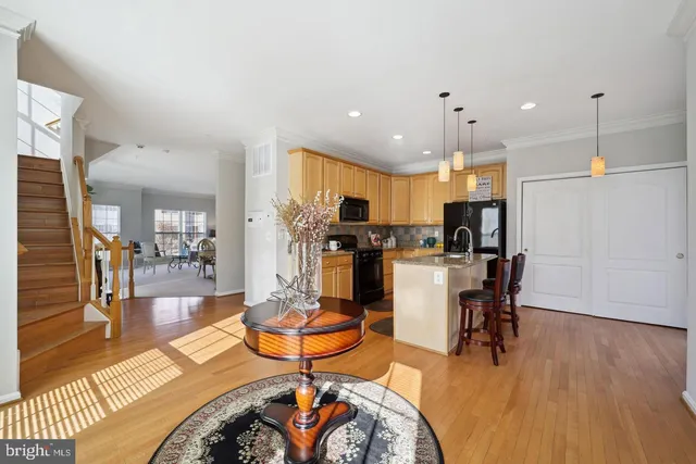 a view of a dining room and livingroom with furniture wooden floor a rug a fireplace and a chandelier