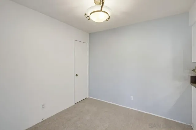 an empty room with a chandelier fan and a window