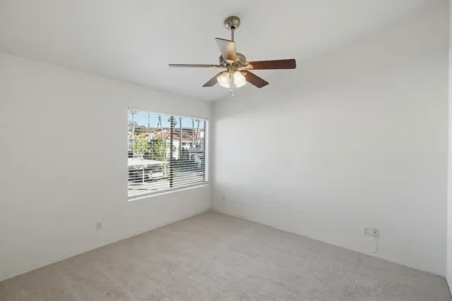 an empty room with windows and ceiling fan