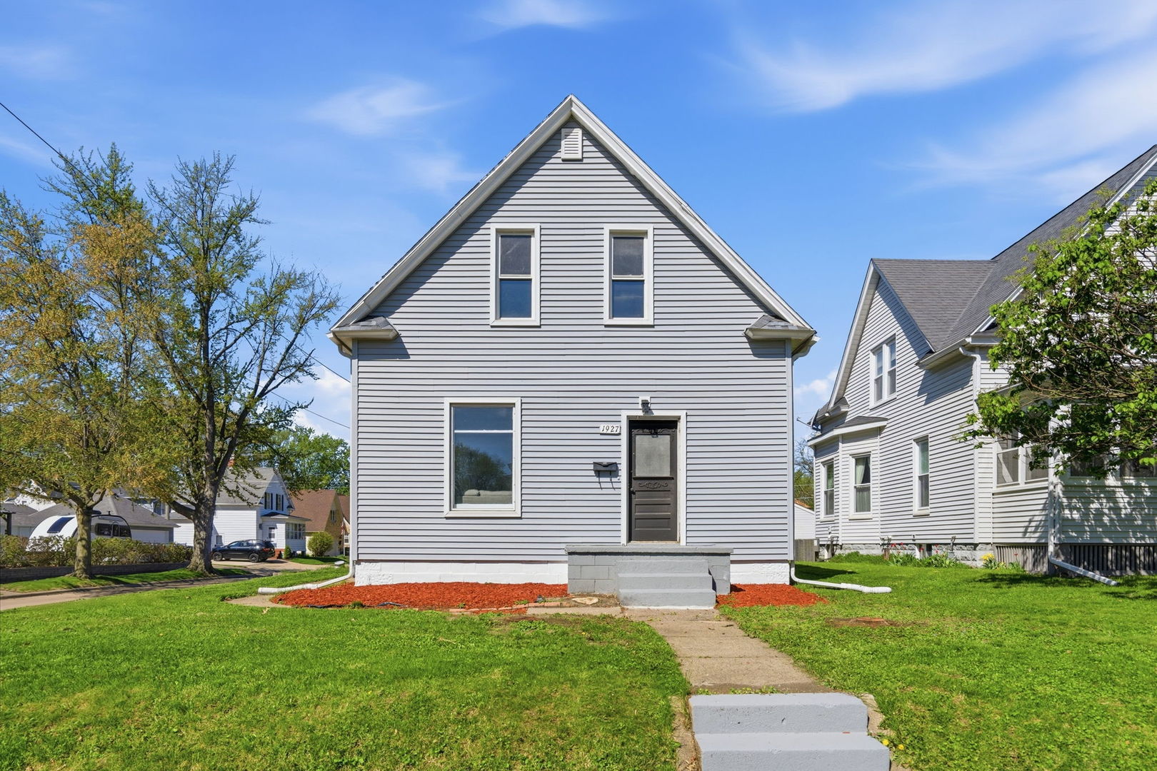 a front view of a house with a yard and trees