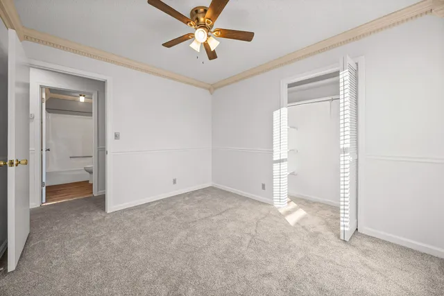 an empty room with closet and a ceiling fan