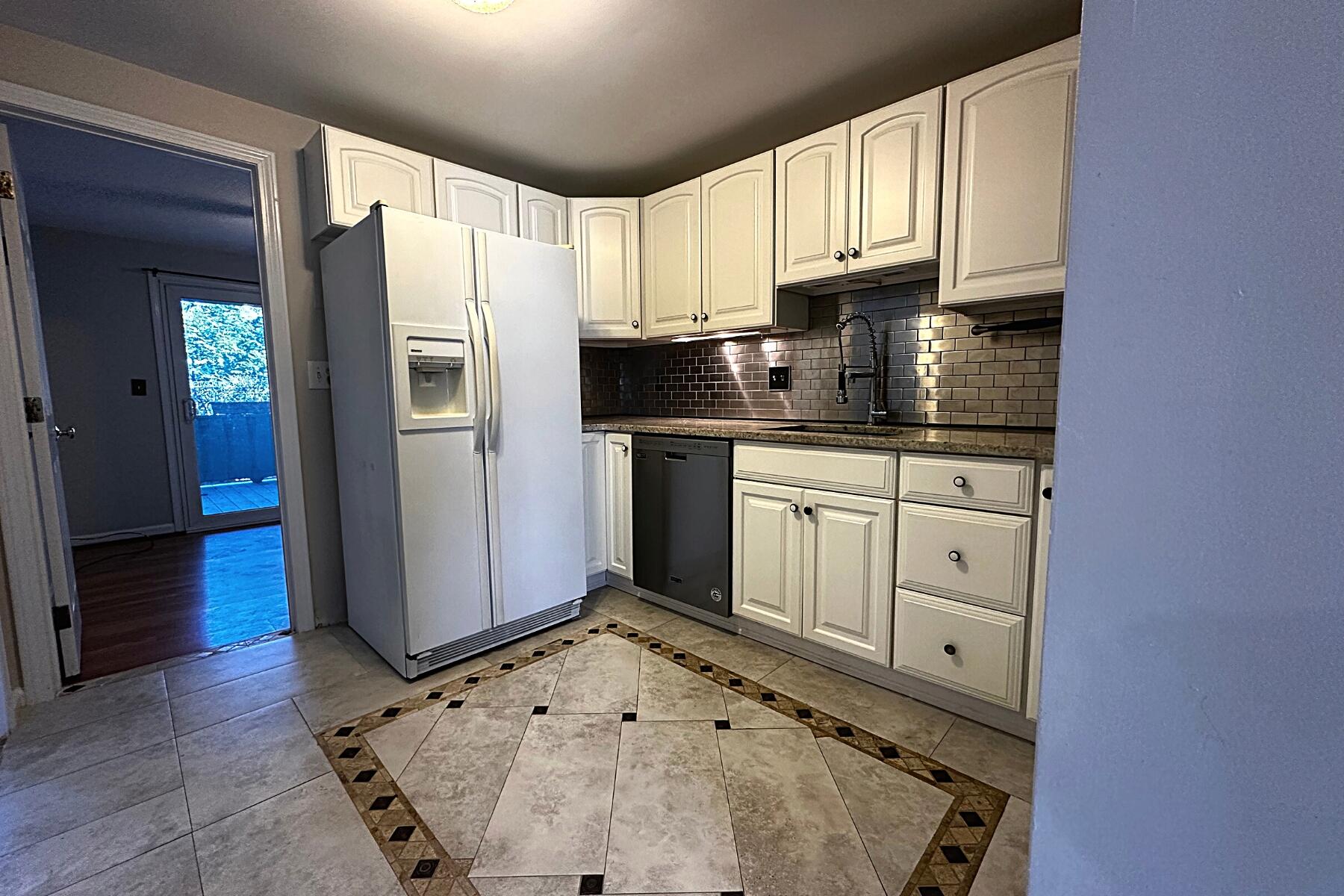 70 North Street, Unit E Hyannis, MA 02601 - Photo 5 of 29 a kitchen with granite countertop a refrigerator sink and cabinets