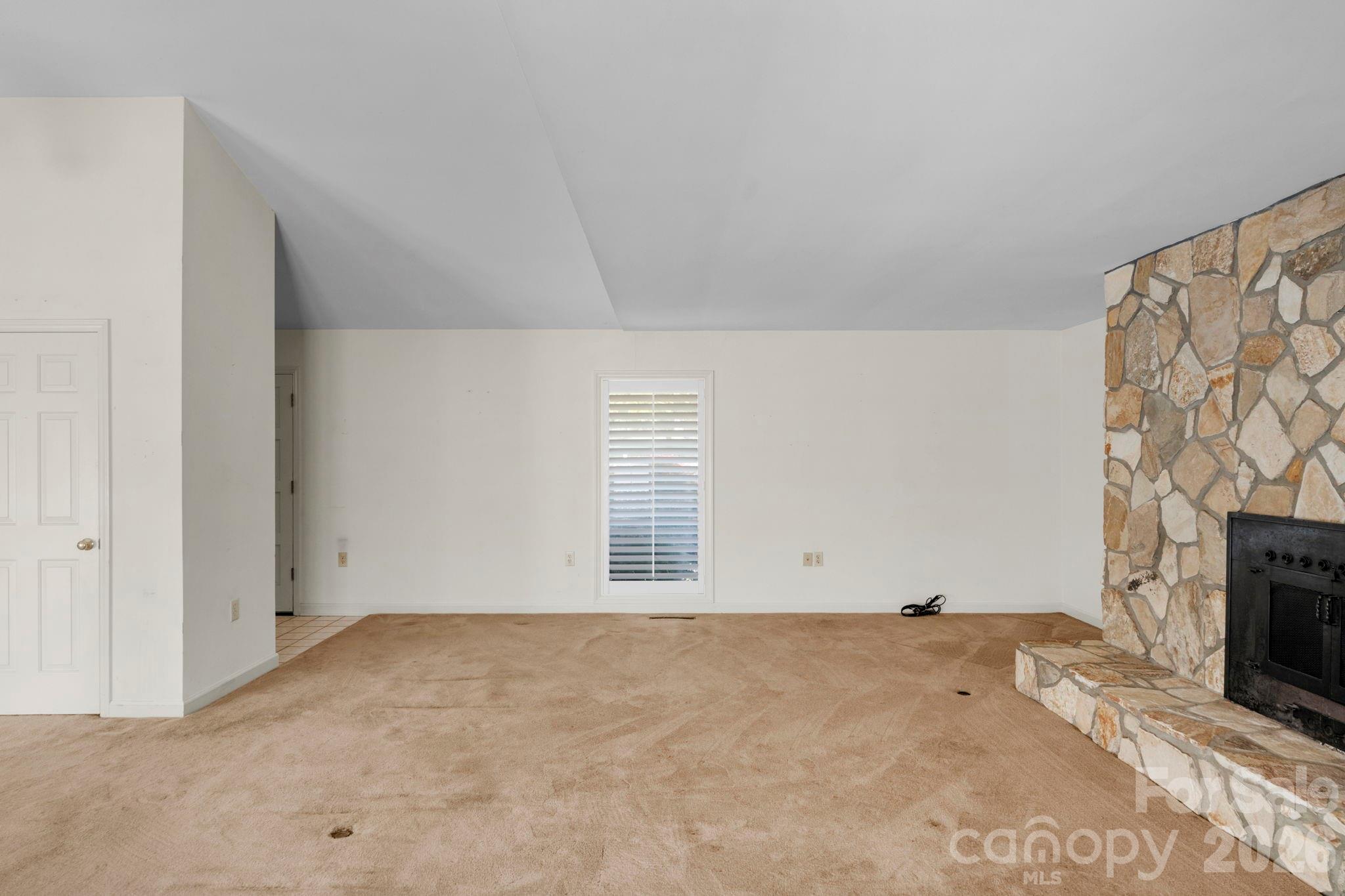 15015 Pawnee Trail Matthews, NC 28104 - Photo 11 of 39 an empty room with a fireplace and wooden floor