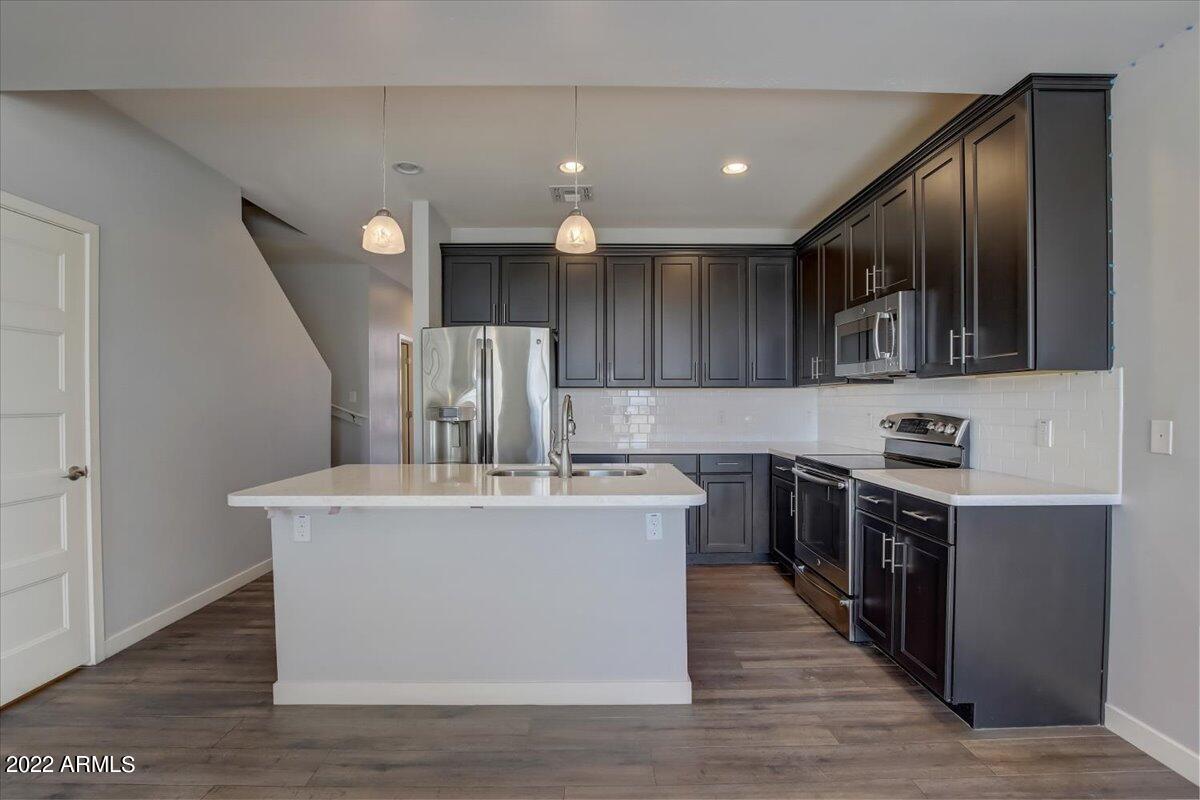 1282 East Curry Road Tempe, AZ 85288 - Photo 54 of 56 a large kitchen with stainless steel appliances granite countertop a stove a sink dishwasher and a refrigerator with wooden floor