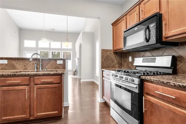 a kitchen with stainless steel appliances granite countertop a stove a sink and a microwave