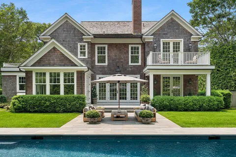 a view of a house with a yard deck and a large tree
