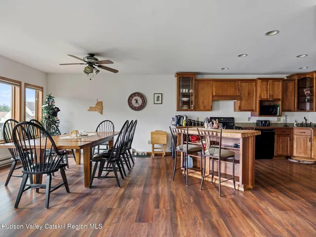 a open kitchen with stainless steel appliances a dining table chairs stove and a wooden floor