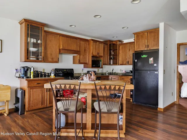 a kitchen with stainless steel appliances granite countertop a refrigerator a stove a sink dishwasher and a dining table with wooden floor