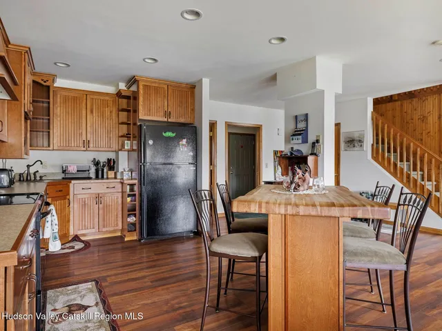 a kitchen with stainless steel appliances granite countertop a refrigerator a stove and a dining table with wooden floor