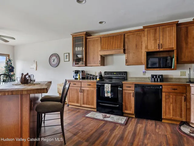 a kitchen with granite countertop a stove top oven a sink dishwasher a dining table and chairs with wooden floor