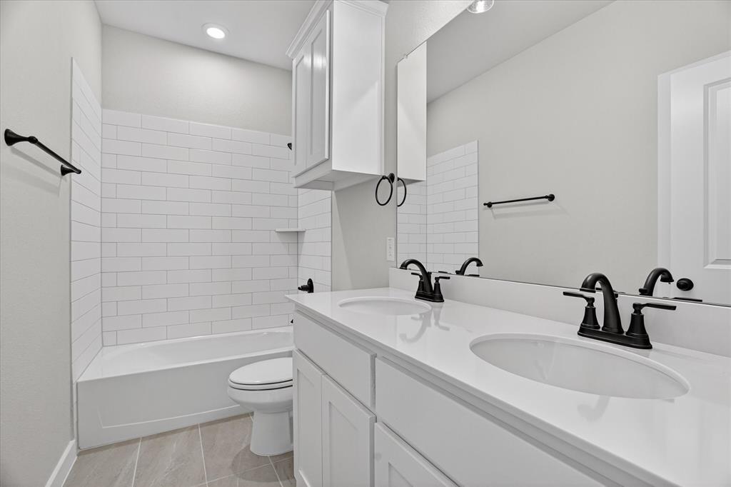 317 Skeen Peak Springtown, TX 76082 - Photo 16 of 31 Bathroom featuring a dual-sink vanity with white countertops, matte black fixtures, a built-in tub with subway tile surround, recessed lighting, and wood-finish flooring