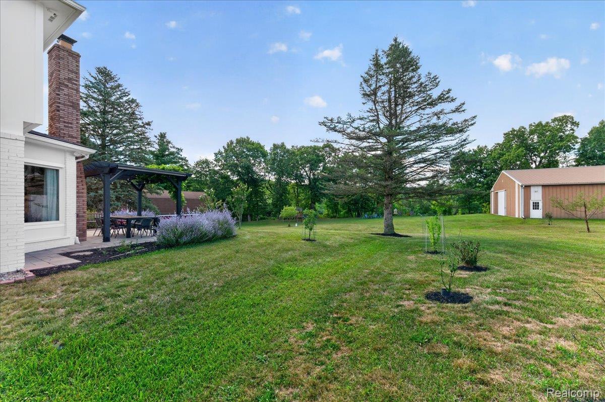 7330 West Gates Street Romeo, MI 48065 - Photo 54 of 73 Expansive lawn with mature trees, a detached barn structure, and a patio featuring a pergola