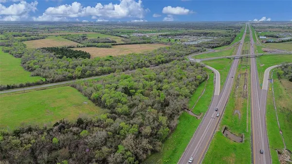 an aerial view of field with trees in the background