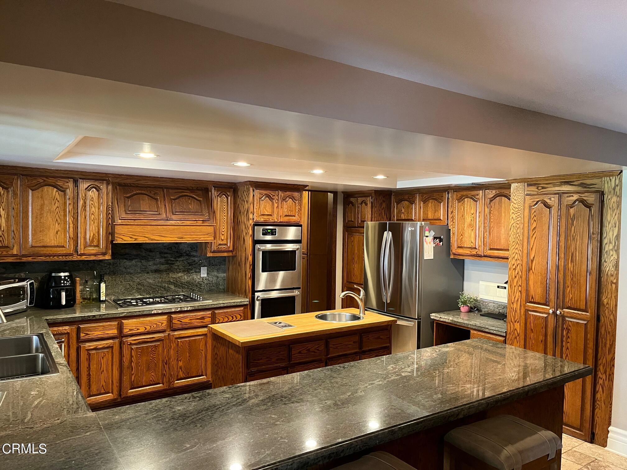 25049 Highspring Avenue Newhall, CA 91321 - Photo 25 of 52 a kitchen with stainless steel appliances granite countertop a refrigerator a sink and a stove