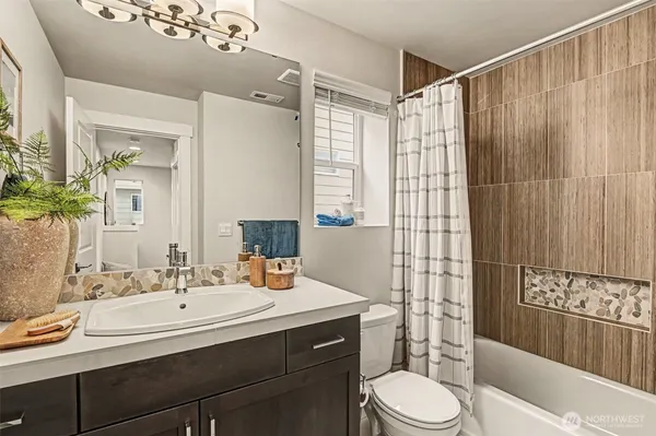 a bathroom with a sink a toilet a mirror a vanity and shower