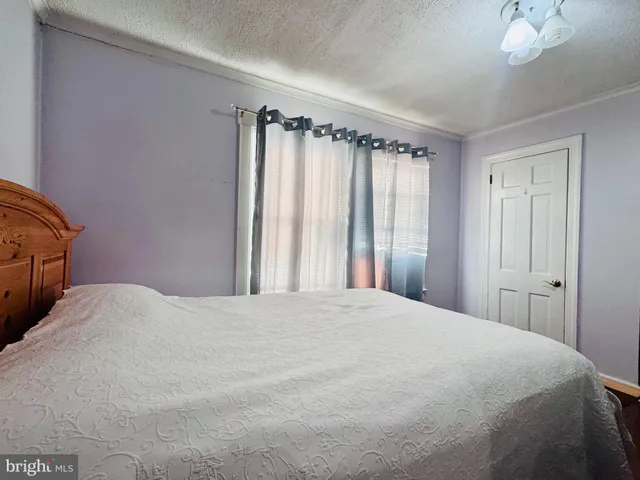 a large white bed in a small room next to a window