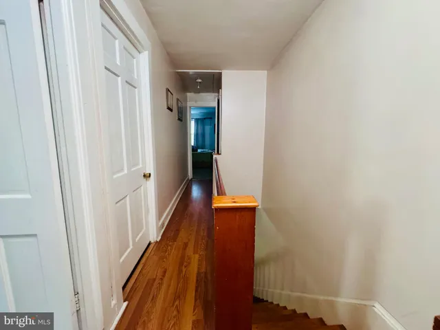 a hallway with wooden floor and stairs