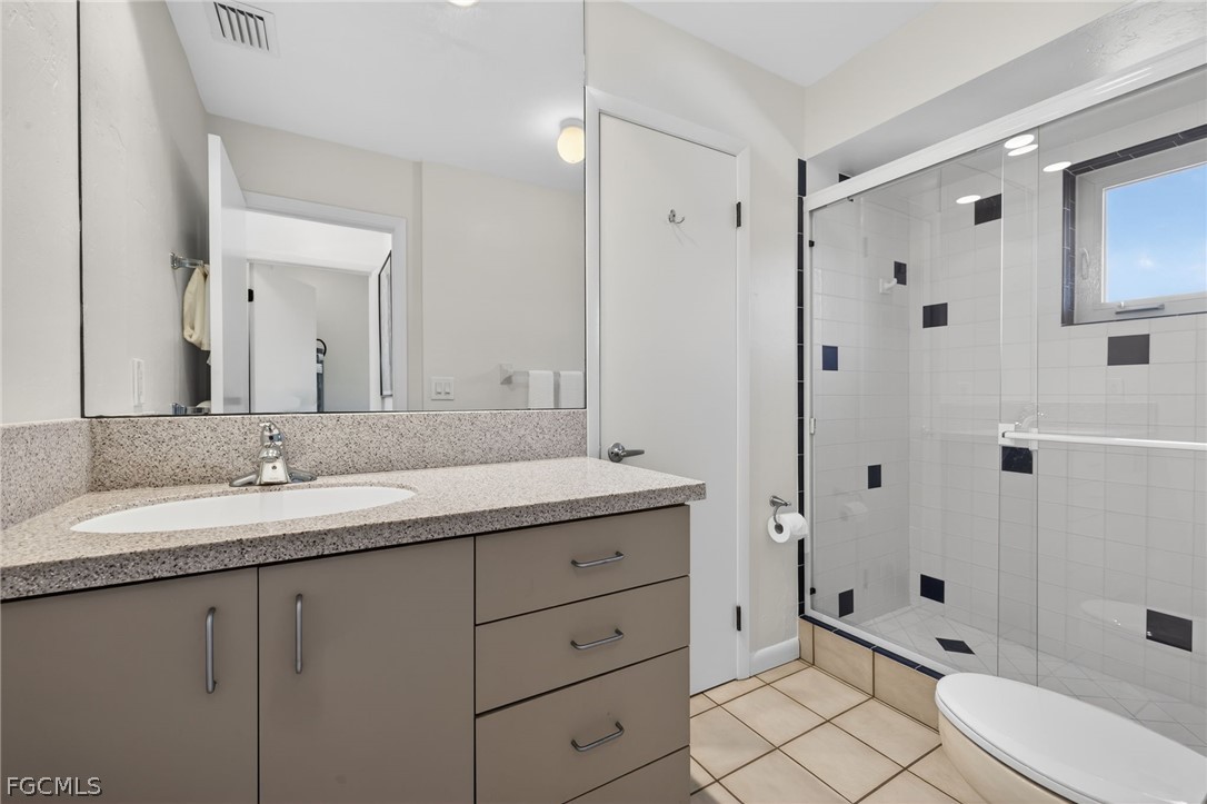 4562 Bowen Bayou Road Sanibel, FL 33957 - Photo 20 of 38 a bathroom with a granite countertop sink toilet a large mirror a shower and a mirror