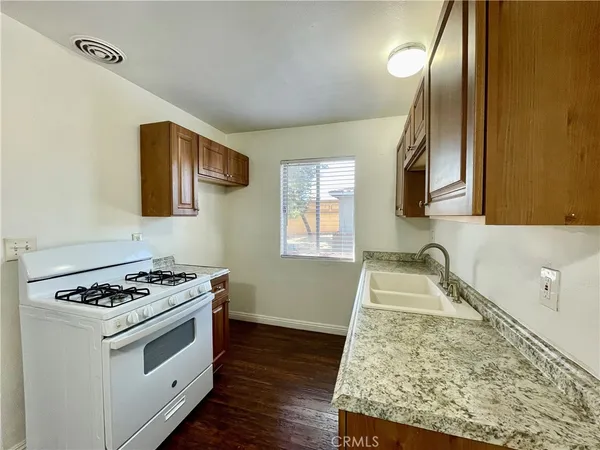 a kitchen with granite countertop a sink stove and cabinets