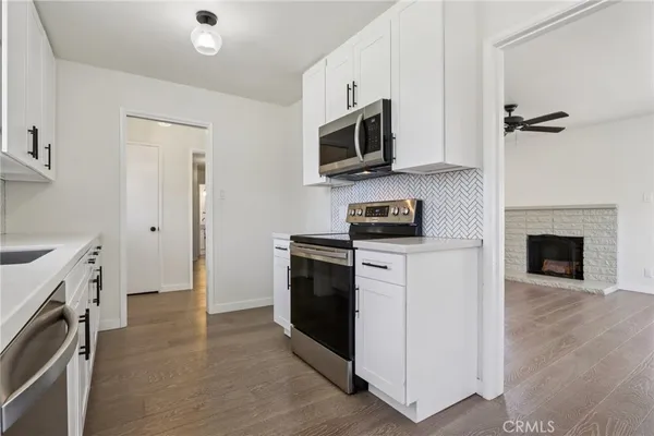 a kitchen with stainless steel appliances white cabinets a stove top oven a sink and dishwasher