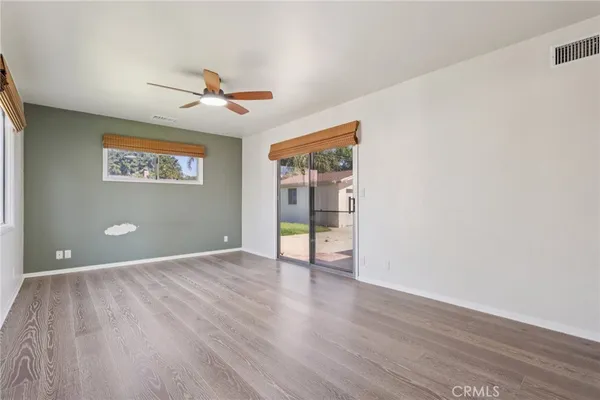 an empty room with wooden floor chandelier fan and windows
