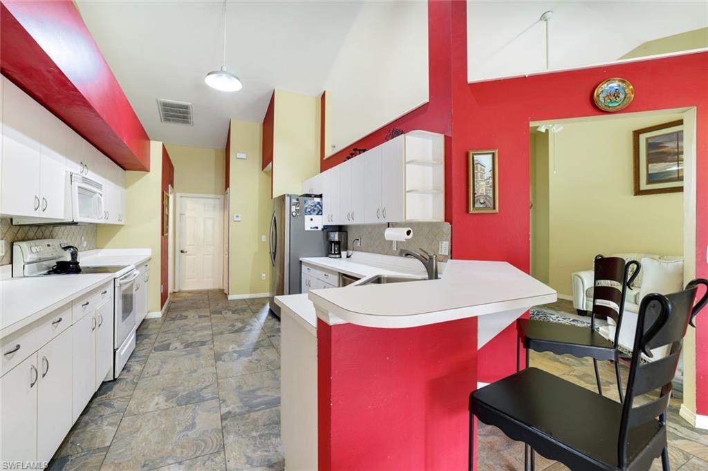 1920 Piccadilly Circus Naples, FL 34112 - Photo 11 of 25 a large kitchen with a table chairs stove and cabinets