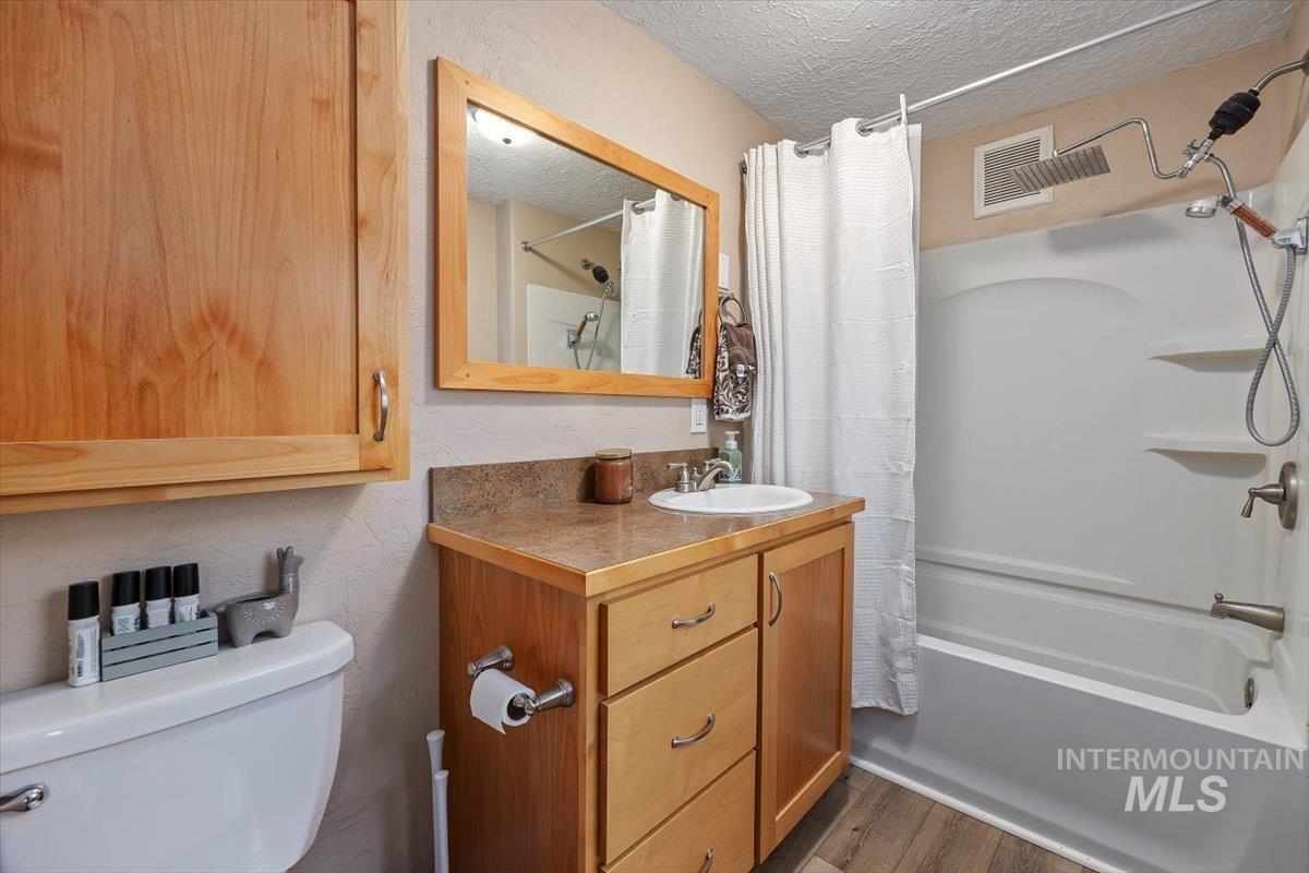 347 Polk Street Twin Falls, ID 83301 - Photo 17 of 25 Full bathroom featuring a textured ceiling, vanity, shower / bath combo, a textured wall, and dark wood-type flooring