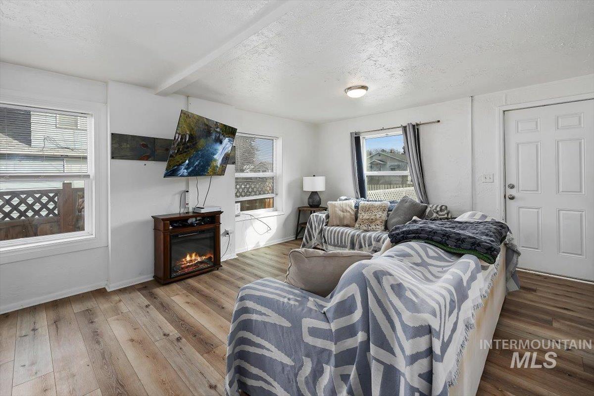 347 Polk Street Twin Falls, ID 83301 - Photo 5 of 25 Living area with hardwood / wood-style flooring, a textured ceiling, beamed ceiling, and a glass covered fireplace