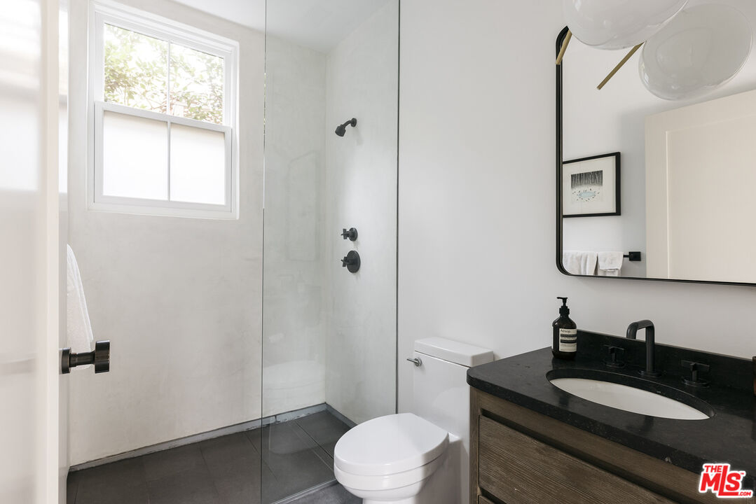 461 West Rustic Road Santa Monica, CA 90402 - Photo 15 of 31 a bathroom with a granite countertop sink toilet a mirror and a window