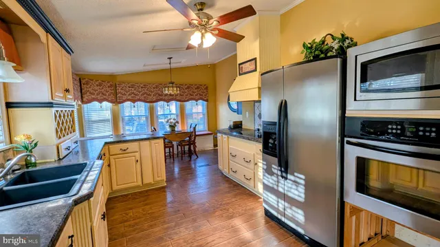 a open kitchen with granite countertop a stove top oven a sink a dining table and chairs with wooden floor