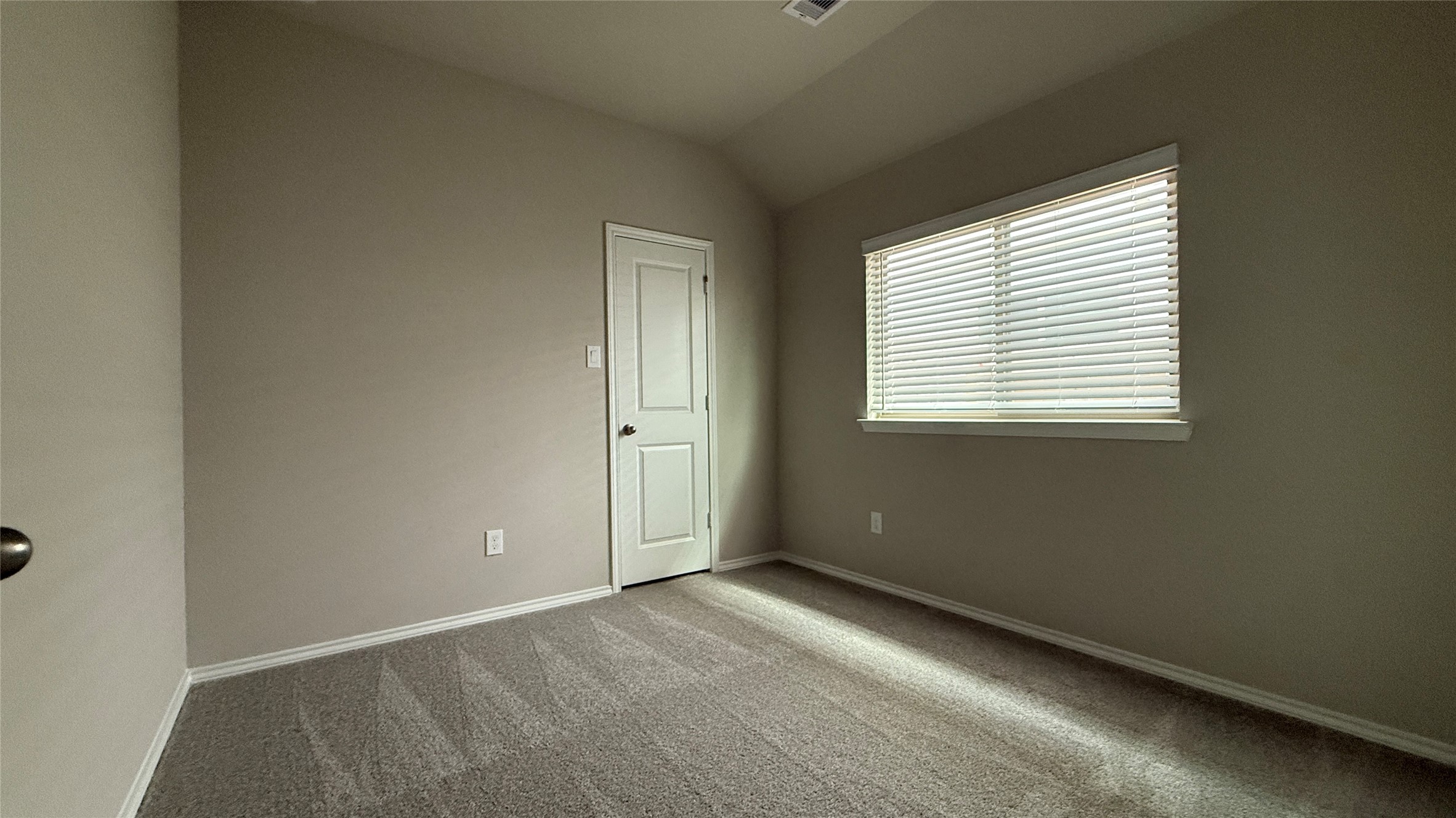 31961 Retama Rnch Drive Spring, TX 77386 - Photo 18 of 25 This is a simple, unfurnished room with carpet flooring, neutral walls, and a window with blinds allowing natural light. There's a door on one wall, likely leading to a closet or hallway.