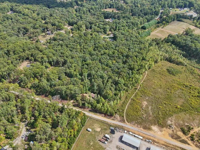 an aerial view of residential house with outdoor space and trees all around