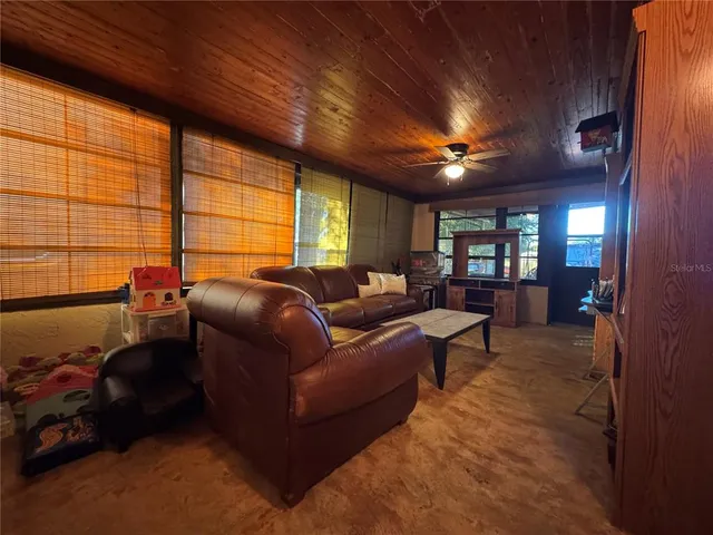 a living room with furniture a ceiling fan and a large window