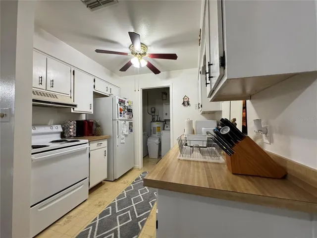 a kitchen with stainless steel appliances kitchen island granite countertop a refrigerator a stove a sink a dining table and chairs with wooden floor