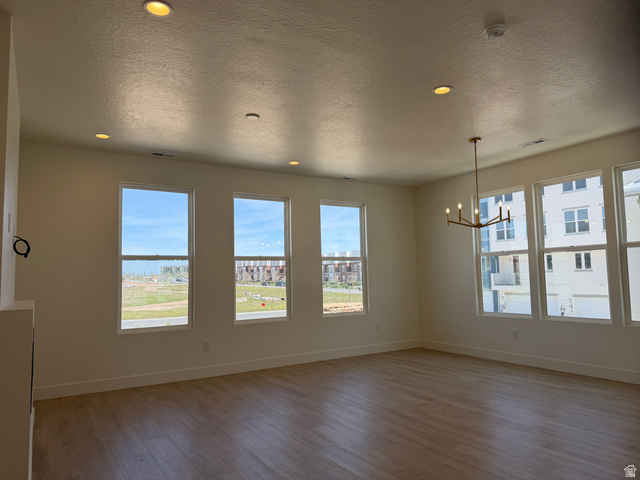 10995 South Freestone Road, Unit 109 South Jordan, UT 84009 - Photo 5 of 20 Empty room with a textured ceiling, hanging lights, dark wood finished floors, and a smoke detector