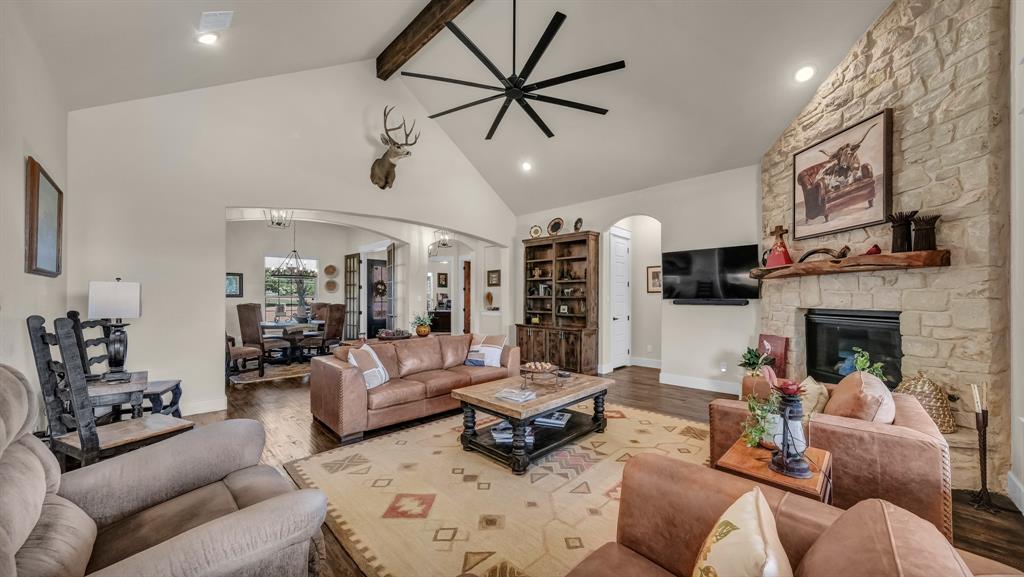 1320 Post Oak Road Gordon, TX 76453 - Photo 14 of 40 Living area featuring a stone fireplace, wood finished floors, beam ceiling, high vaulted ceiling, and arched walkways