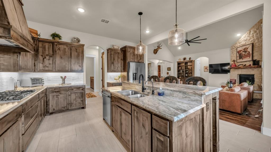 1320 Post Oak Road Gordon, TX 76453 - Photo 20 of 40 Kitchen with arched walkways, vaulted ceiling, pendant lighting, an island with sink, and backsplash