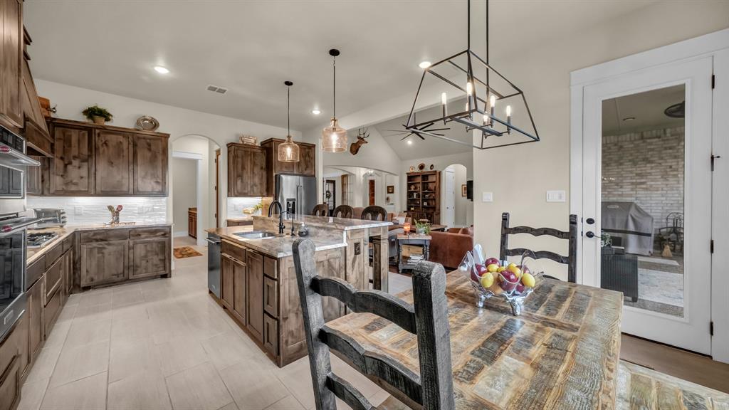 1320 Post Oak Road Gordon, TX 76453 - Photo 23 of 40 Kitchen with vaulted ceiling, arched walkways, backsplash, a kitchen island with sink, and decorative light fixtures