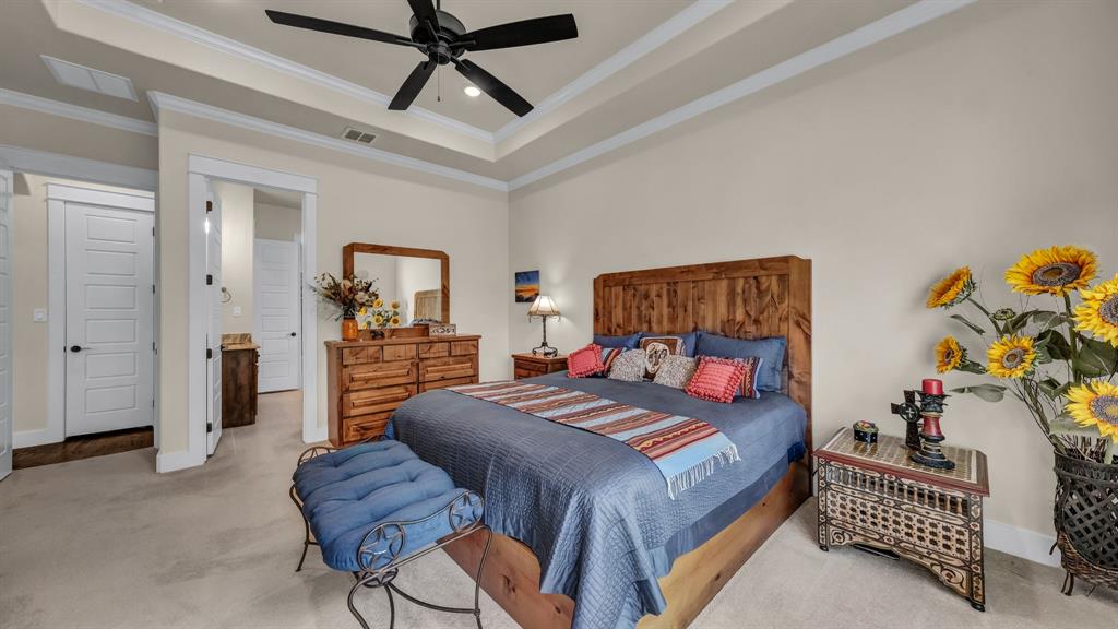 1320 Post Oak Road Gordon, TX 76453 - Photo 32 of 40 Carpeted bedroom with a raised ceiling, connected bathroom, recessed lighting, ceiling fan, and ornamental molding