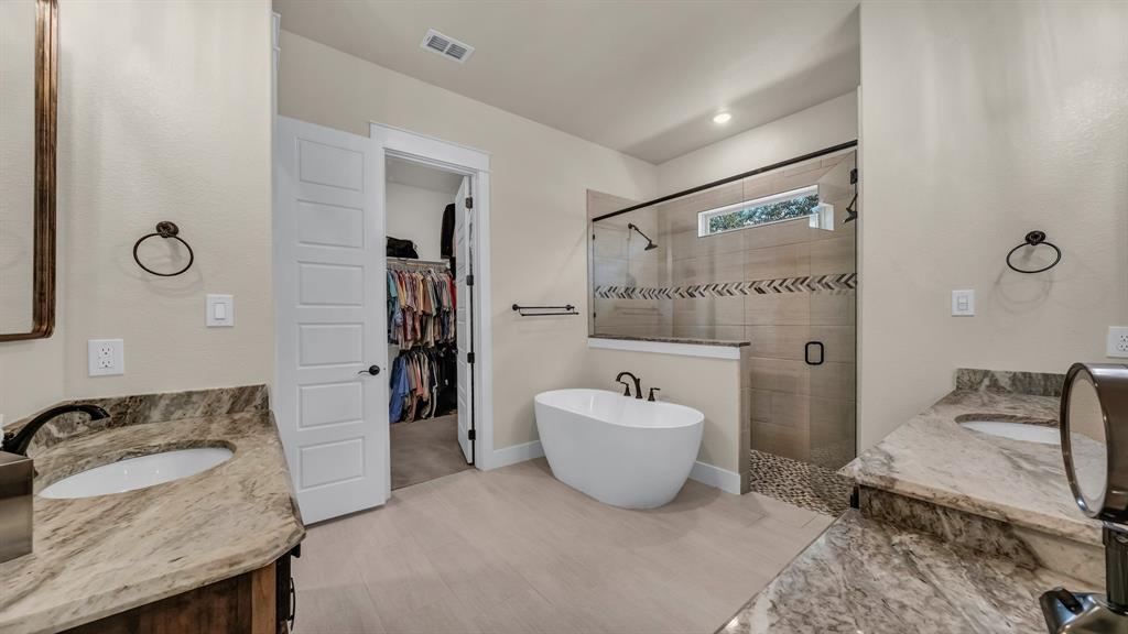 1320 Post Oak Road Gordon, TX 76453 - Photo 34 of 40 Bathroom featuring two vanities, a shower stall, a freestanding tub, and a spacious closet
