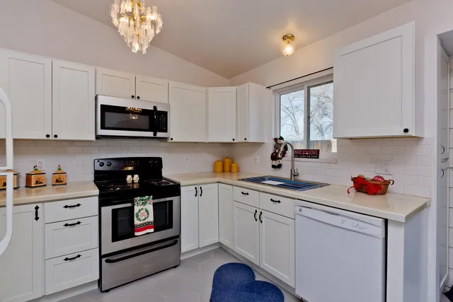 a kitchen with stainless steel appliances a white stove top oven a sink a window and cabinets