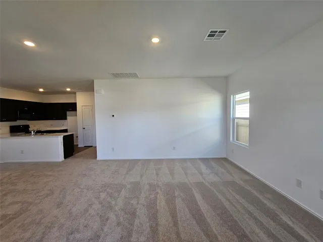 an empty room with kitchen view and a window