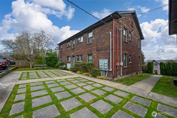 a view of a brick house with many windows next to a yard