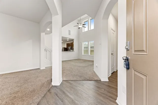 a view of an empty room with kitchen and a window