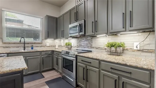 a kitchen with a stove a refrigerator and a dining table with wooden floor