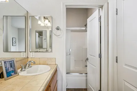 a bathroom with a tub sink vanity granite and mirror