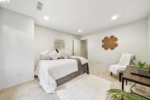 a bedroom with a bed a couch and a potted plant
