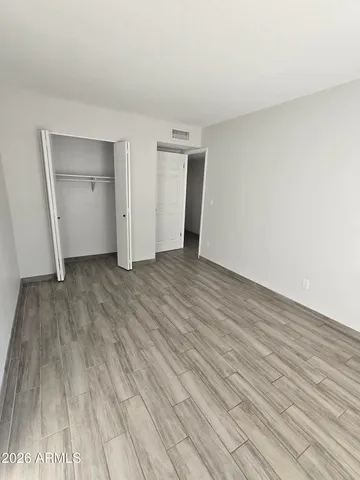 a view of an empty room with wooden floor and closet