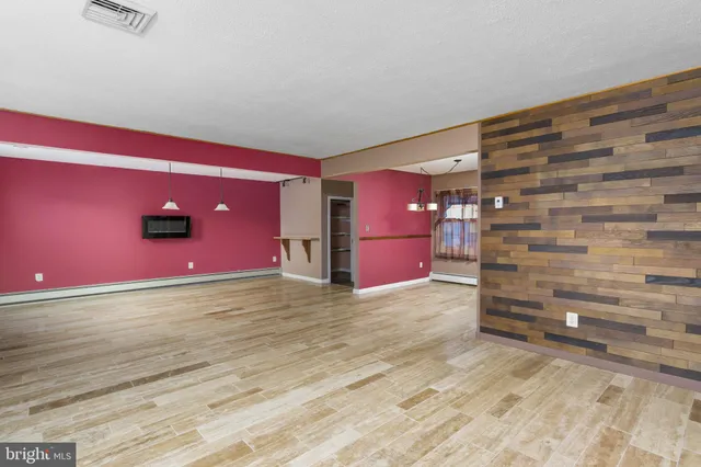 a view of an empty room with window and wooden floor